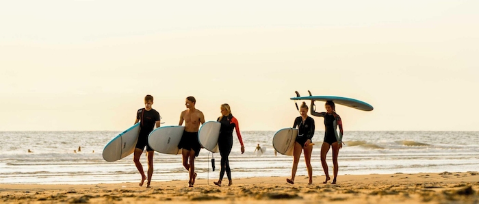 Jongeren wandelen op het strand tijdens de jongerenreis surfen
