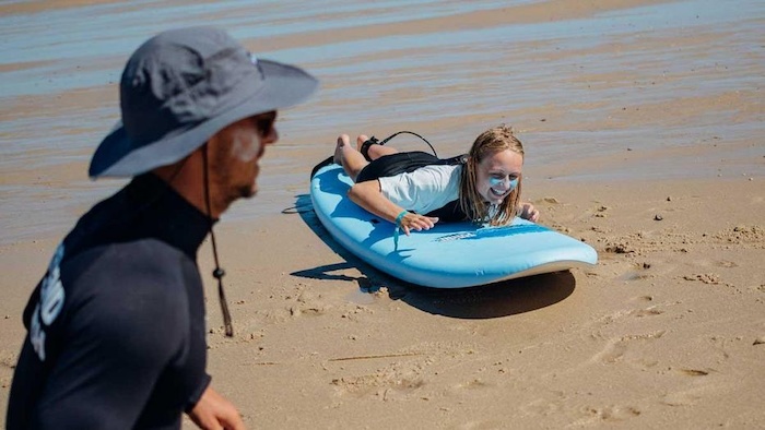 Een meisje krijgt les tijdens de groepsreis surfen