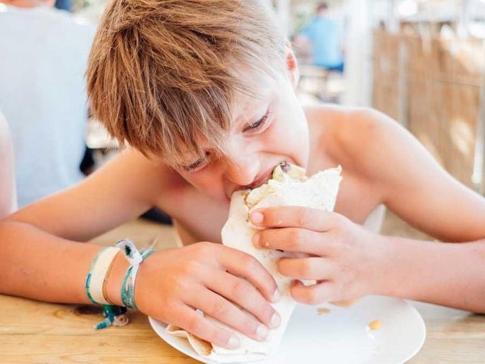 Jongen bijt in gezonde wrap tijdens zomerkamp kinderen