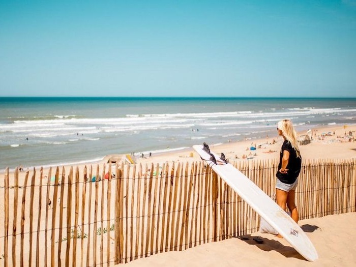 Alternatief op kamp Brugge, meisje met surfboard kijkt naar het strand