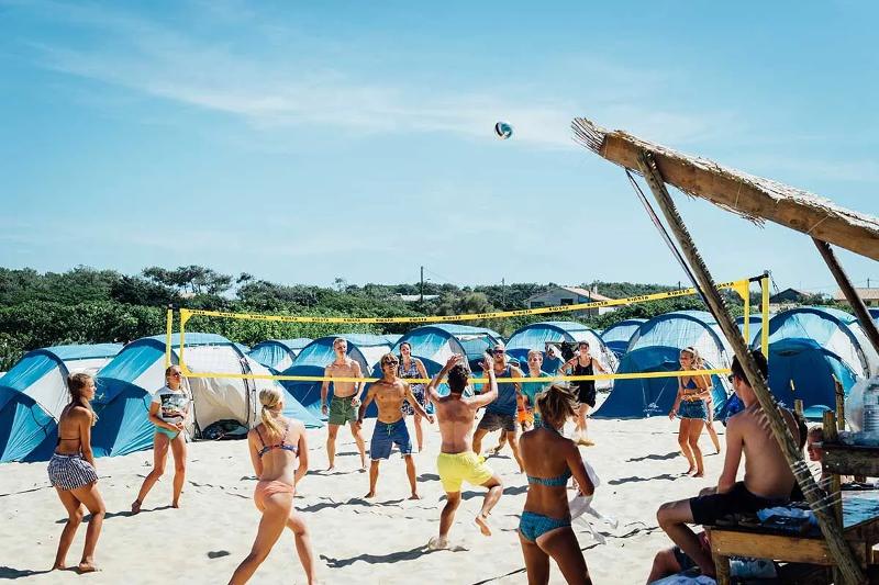 Jongeren spelen beachvolleybal tijdens een surfkamp 16 jaar
