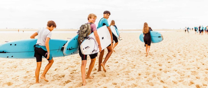 Kinderen die hun surfboard dragen tijdens de Surfkampen Europa