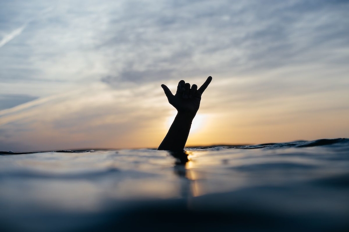 Een hand uit het water tijdens de groepsreis surfen