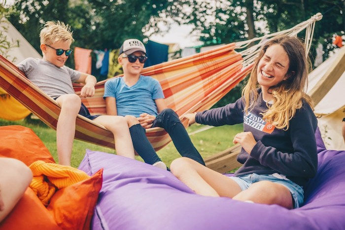 Jongens en meisjes aan het lachen op de hangmat tijdens zomerkamp Nederland