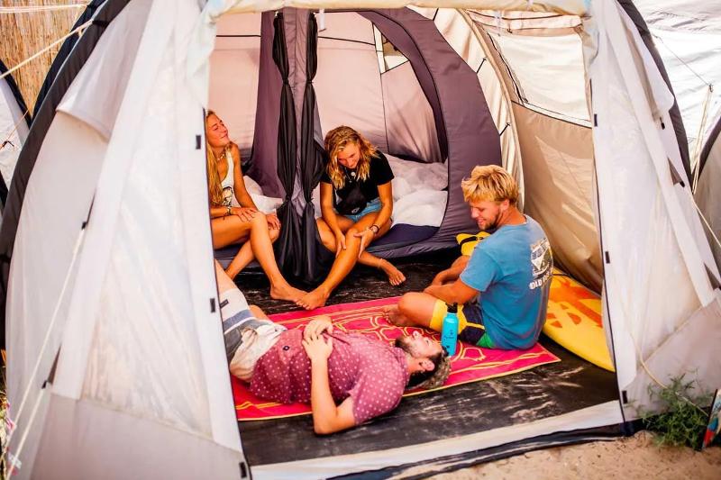 Een groepje deelnemers aan het surfkamp 14 jaar rust even uit in de tent