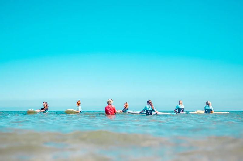 Deelnemers van een surfkamp Zarautz krijgen surfles van een begeleider in het water