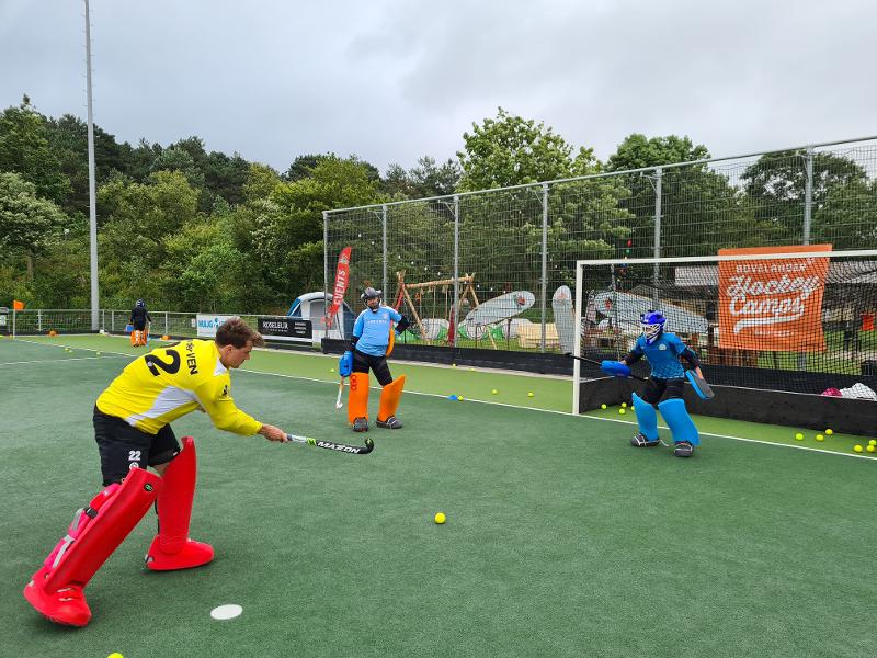 een jongen in een geel shirt scoort een goal in hockeykamp zandvoort