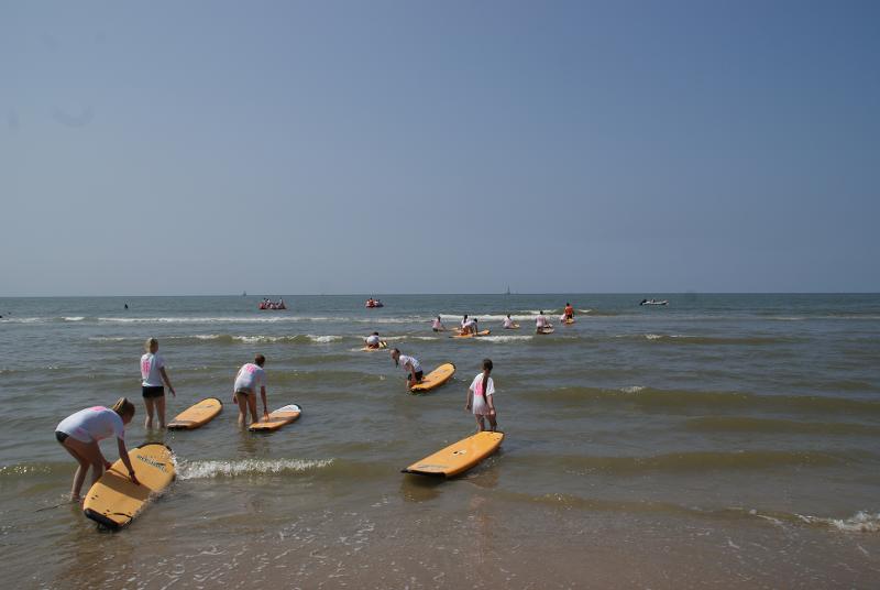 Twee meisjes zitten op de hurken op het strand tijdens een hockeykamp in Zandvoort