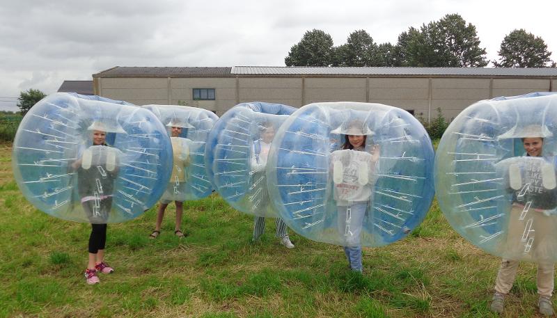 Kinderen staan in een opblaasbare bal in de natuur en spel tijdens een Duits taalkamp