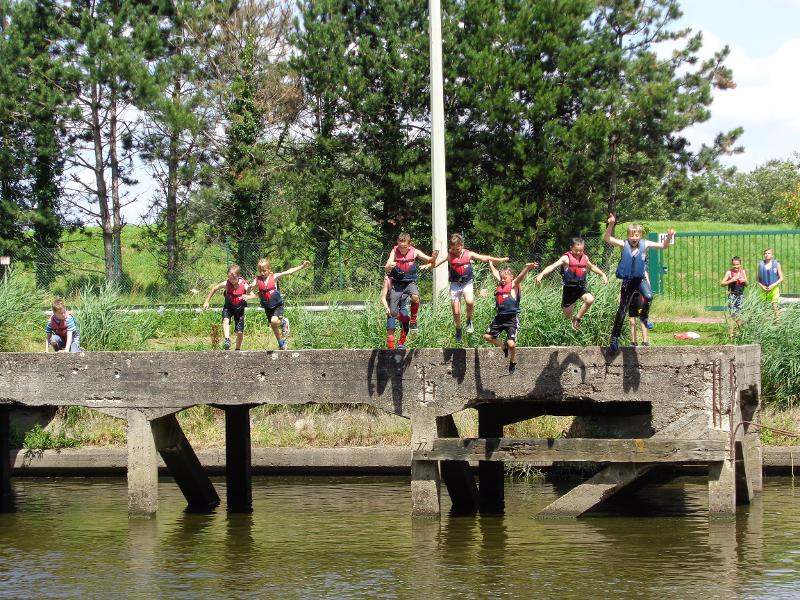 Kinderen springen het water in tijdens sportkamp