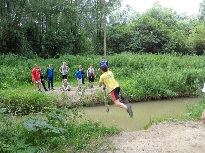 jongen springt over sloot met touwen slinger op tenniskamp
