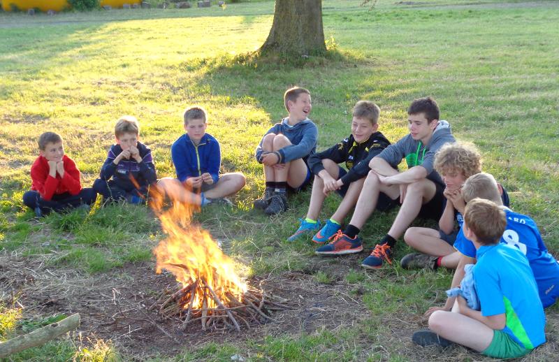Kinderen hebben plezier rondom het kampvuur tijdens een zomerkamp