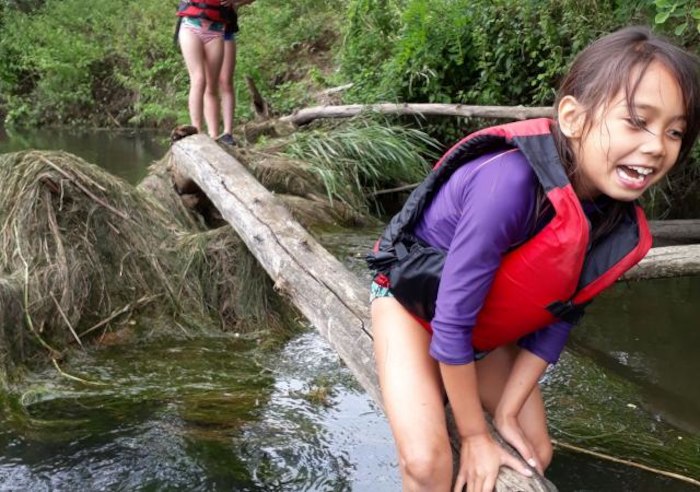 Meisje zit op balk in rode reddingsvest op vakantiekamp