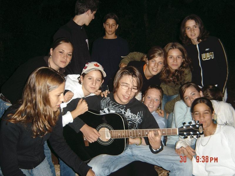 groupe de jeunes avec une guitare le soir en colo de vacances