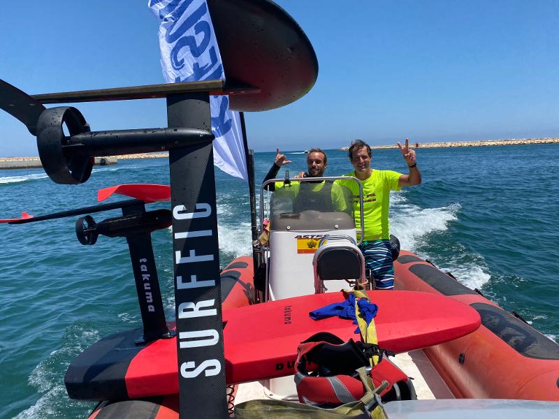 twee begeleiders op een boot steken de hand in de lucht tijdens een watersportkamp