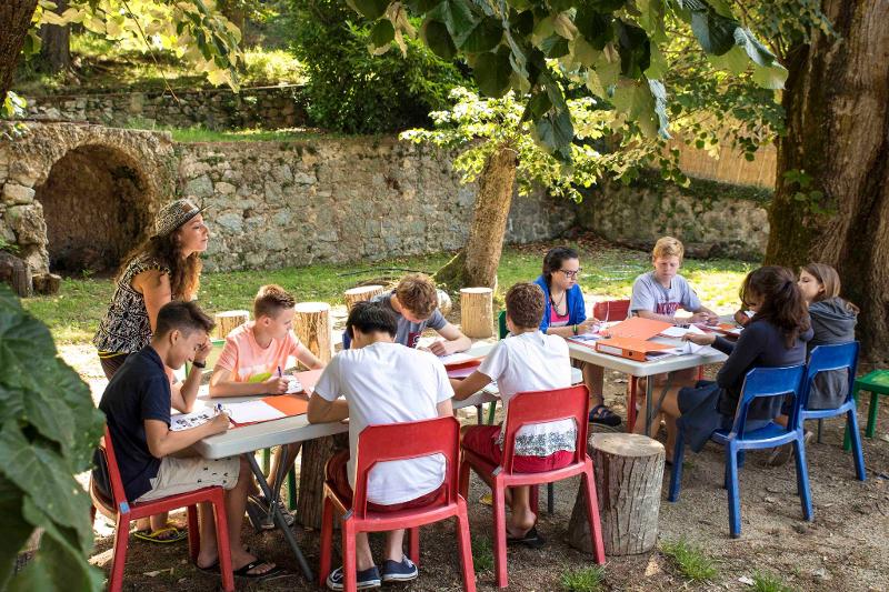 Deelnemers tijdens taalkamp zitten rond een tafel