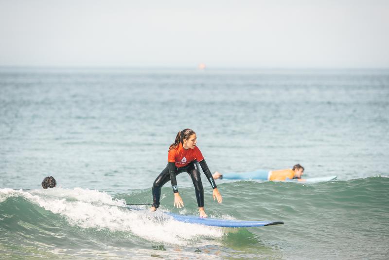 Een deelnemer van een surf taalreis surft over een golf heen