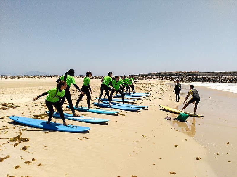 Jongeren tijdens taalreis leren te surfen op het strand