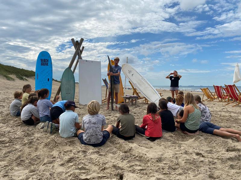 Jongeren luisteren naar de surfles op jongerenvakantie