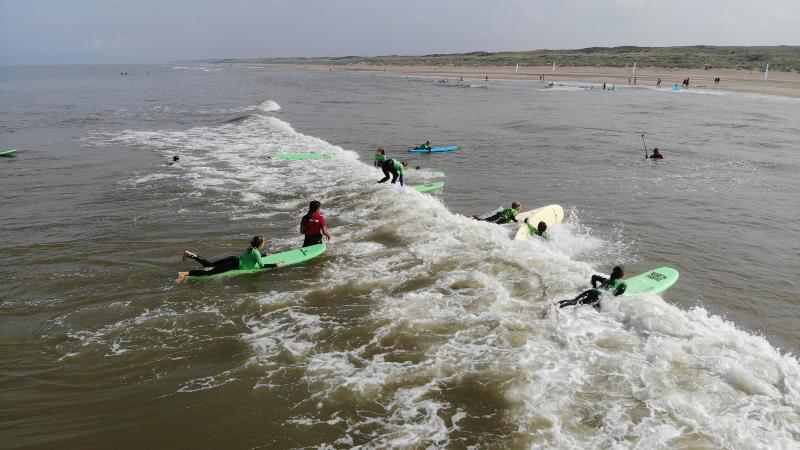 Jongeren surfen in groep op jongerenvakantie 17 jaar