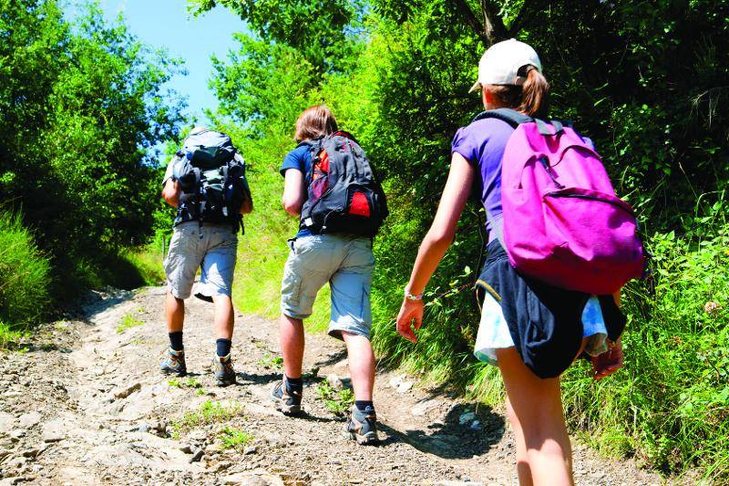 enfants avec un sac à dos en randonnée au soleil en colonie aventure