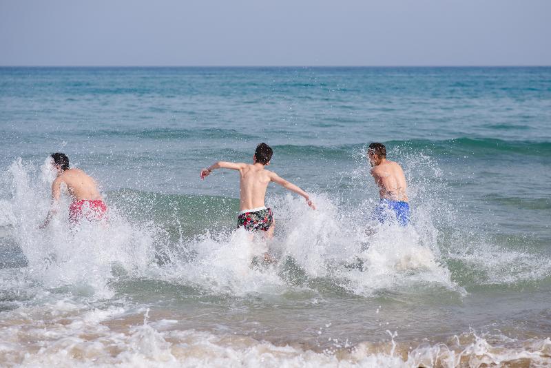 Drie jongen rennen de zee in tijdens jongerenreis Spanje