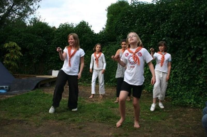 Kinderen dansen in een tuin tijdens een zomerkamp in de Ardennen