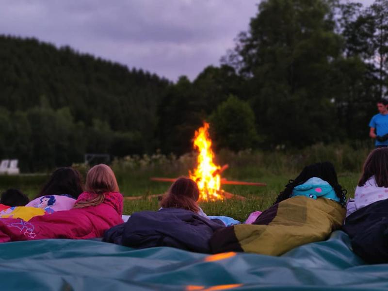 Kinderen liggen bij het kampvuur op knutselkamp