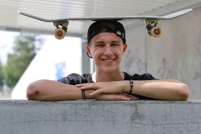 Jongen met een skateboard op zijn hoofd tijdens een skatekamp