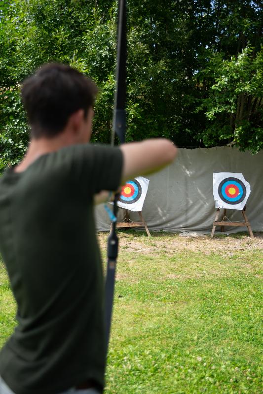 jongen schiet pijl en boog op een rond doelwit tijdens een natuur kamp in zweden