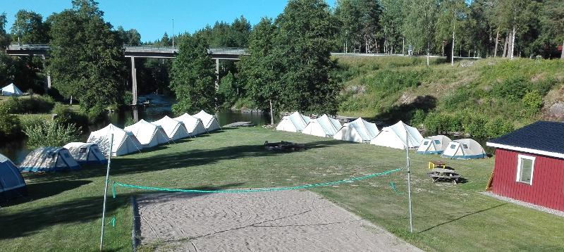 witte tenten staan op een rij op een grasveld tijdens een natuur kamp in zweden