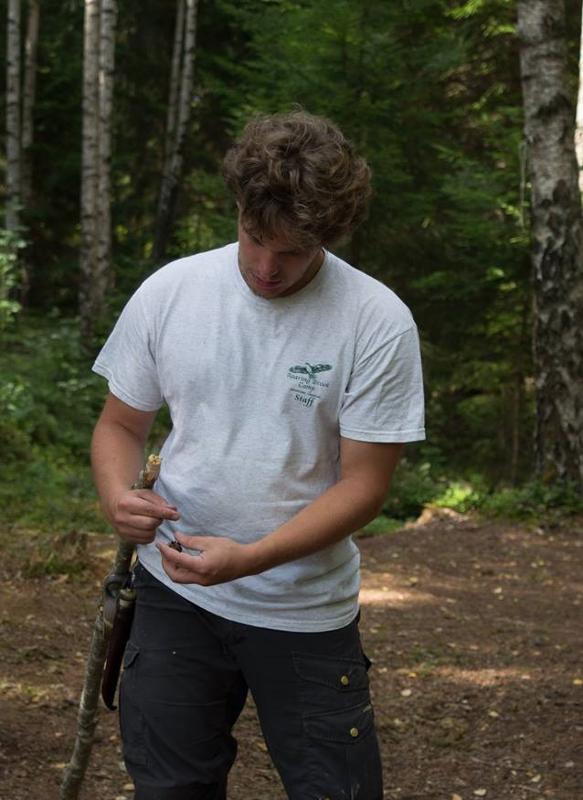 Jongen in het bos met tak tijdens natuurkamp in Zweden