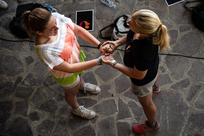 Twee meiden houden elkaar de hand vast voor een opdracht tijdens Jongerenreizen Italië
