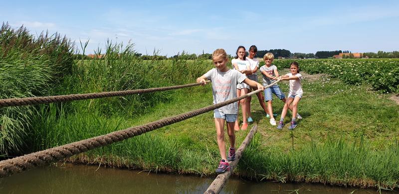 kinderen springen slootje op boerderij kamp