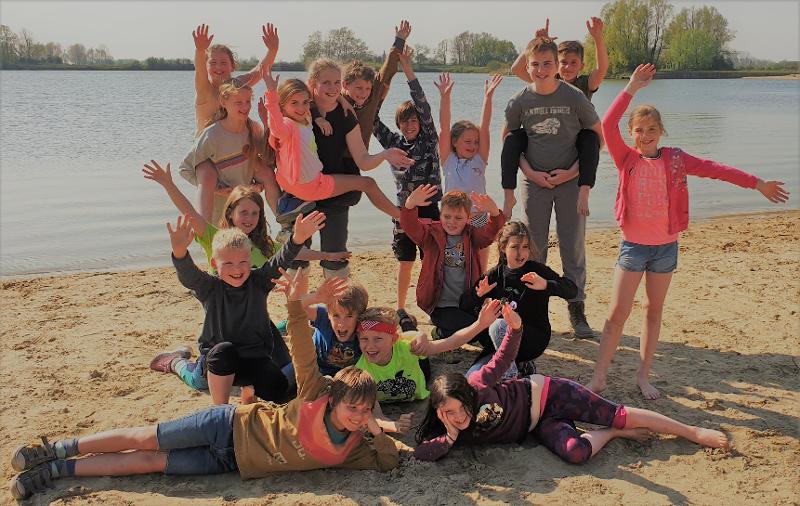 Groep kinderen zwaait naar de camera voor een leer tijdens een viskamp