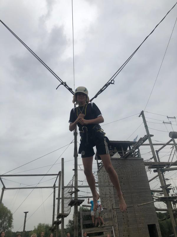 jeune garçon accroché en tyrolienne dans l'air en stage linguistique sportif