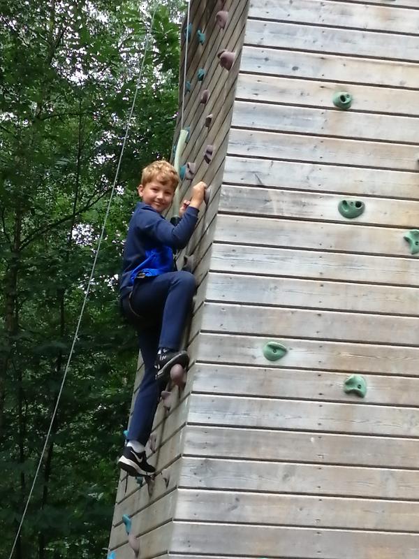 Jongen beklimt een muur tijdens een avonturenkamp in ronse