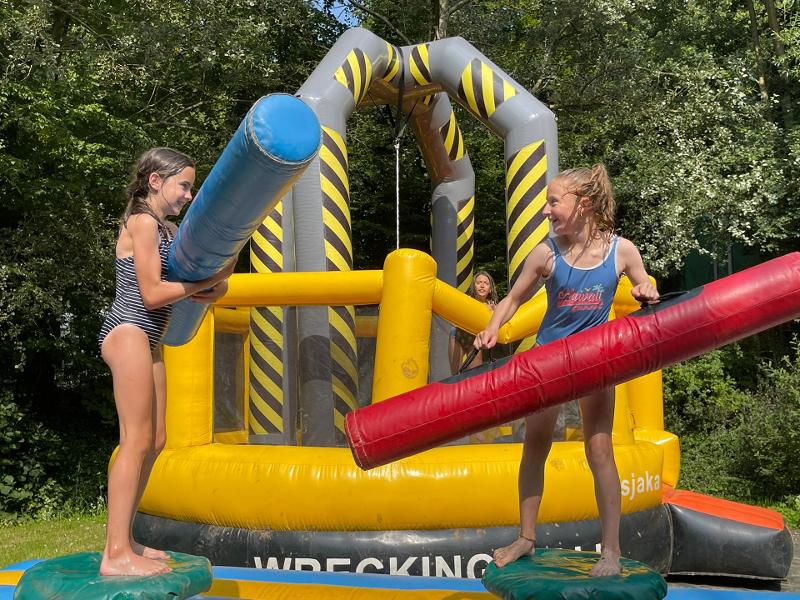 deux jeunes filles en maillot de bain sur un équipement gonflable avec des frites gonflables dans les mains en colonie nautique