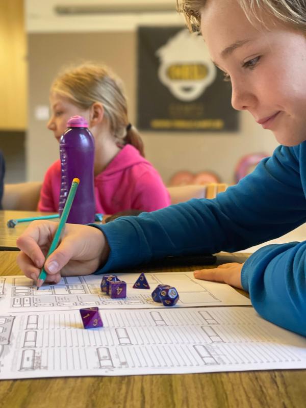 Jongen is aan het schrijven tijdens een dungeon and dragons kamp