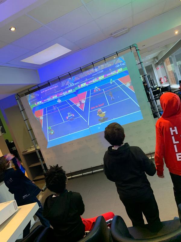 Jongens doen gamespel op een beamer tijdens een game kamp
