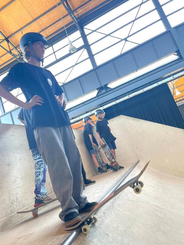 jongen staat bovenaan halfpipe in de verte te kijken op skatekamp in schoten