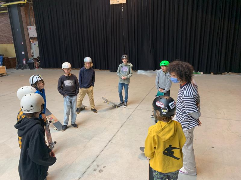 enfants avec des casques qui écoutent l'animateur en skateboard stage