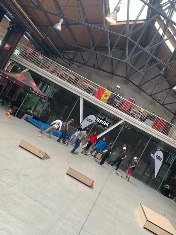 jongens in de grote skatehal luisteren naar uitleg van een pro skater op skatekamp in schoten