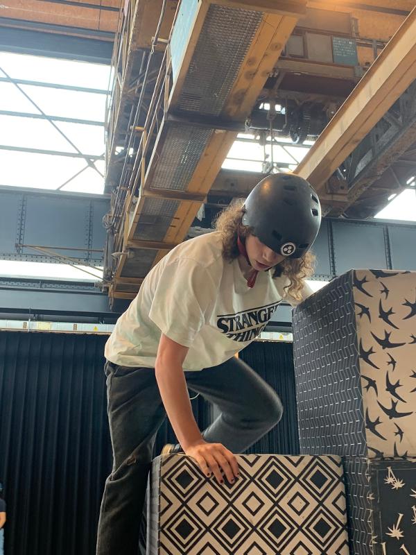 jongen met helm klimt op trap gemaakt van blokken tijdens skate kamp in schoten