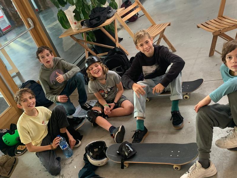 jongens nemen een pauze en zitten op hun skateboard tijdens skate kamp in schoten