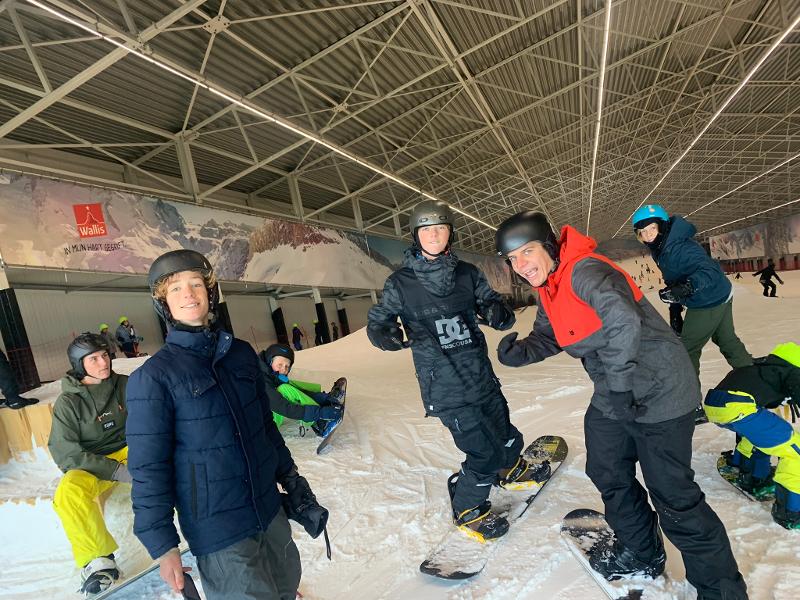 groepje jongeren lachen voor de groepsfoto met snowboard tijdens skate kamp in schoten