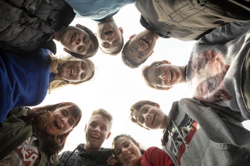 groupe de jeunes en rond qui regarde la caméra en bas en souriant en stage linguistique néerlandais