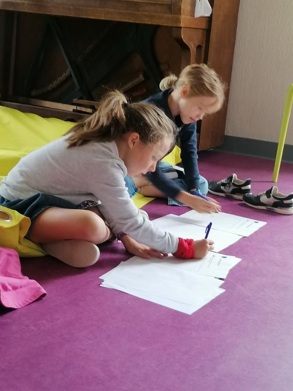 twee meisjes zitten op de grond en schrijven een script op muziekkamp 