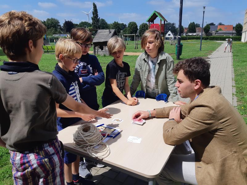 jongens zitten buiten aan tafel een spel te spelen op muziek kamp