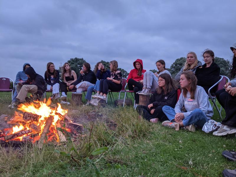 Jongens en meisjes zitten bij het kampvuur op taalreis Engels
